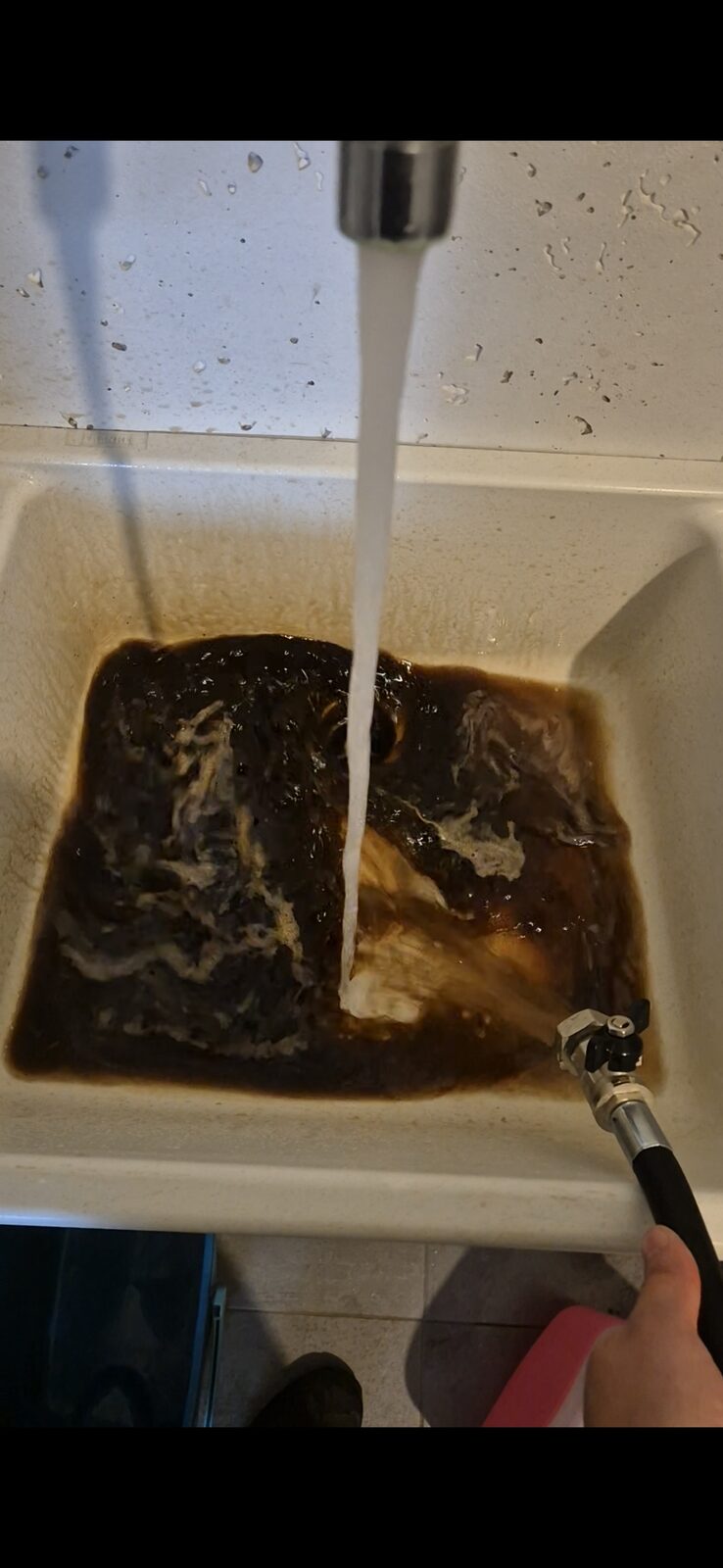 Résultat du désembouage : eau noire chargée de boues ferreuses extraites du circuit de chauffage